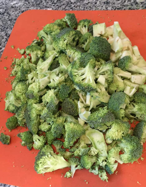 chopped broccoli on an orange plastic cutting board